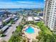 View of the community pool, hot tub, and condo building with palm trees and lounge chairs at 400 Island Way # 502, Clearwater Beach, FL 33767
