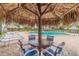 Shaded poolside seating area with chairs and tables under a tiki hut at 400 Island Way # 502, Clearwater Beach, FL 33767