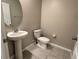 Simple half-bathroom with pedestal sink, standard toilet, and neutral wall color and grey tile flooring at 4448 Globe Thistle, Tampa, FL 33619