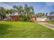 Charming home with a large grassy front yard, palm trees, and a driveway leading to a garage at 51 Cypress Dr, Palm Harbor, FL 34684