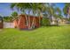Charming home with a large grassy front yard, palm trees, and a driveway leading to a garage at 51 Cypress Dr, Palm Harbor, FL 34684