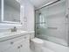 Bright bathroom featuring a shower over tub with glass doors, white vanity, and neutral accents at 599 Westwinds Dr # 9, Palm Harbor, FL 34683