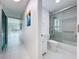 Hallway view with bathroom featuring a shower over tub with glass doors and fixtures at 599 Westwinds Dr # 9, Palm Harbor, FL 34683
