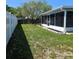 Spacious backyard featuring green grass, a white fence, and a screened patio at 6008 Firefly Ln, Apollo Beach, FL 33572