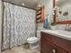 Renovated bathroom with white vanity, and decorative patterned shower curtain, enhanced by fresh decor and shelf at 630 Mac Crillus Rd, Largo, FL 33770