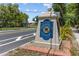 Welcoming Whitfield Estates neighborhood entrance sign, landscaped with lush greenery and a blue and gold emblem at 6921 8Th Street E Ct, Sarasota, FL 34243
