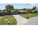 Well-maintained home featuring a green roof, long driveway, green lawn, and mature landscaping at 6921 8Th Street E Ct, Sarasota, FL 34243