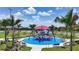 Community playground with unique climbing structure on bright blue surfacing material surrounded by benches and palm trees at 7420 Paradiso Dr, Apollo Beach, FL 33572
