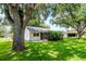 Backyard view showing the house, lawn, and large mature trees at 8626 Woodbridge Dr, New Port Richey, FL 34655
