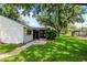 Backyard view showing the house, lawn, and large mature trees at 8626 Woodbridge Dr, New Port Richey, FL 34655