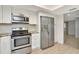Bright kitchen featuring stainless steel appliances, crisp white cabinetry, and wood-look tile flooring at 8626 Woodbridge Dr, New Port Richey, FL 34655