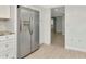 Spacious kitchen boasts stainless steel refrigerator, white cabinets, and seamless flow to hallway at 8626 Woodbridge Dr, New Port Richey, FL 34655