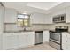 Modern kitchen featuring stainless steel appliances, bright white cabinets, and a neutral backsplash at 8626 Woodbridge Dr, New Port Richey, FL 34655