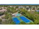 Overhead view of tennis courts, a pool, and homes with a lake in the distance at 899 Addison Ne Dr, St Petersburg, FL 33716