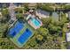 Aerial view of community amenities including tennis courts, pool, volleyball, and playground amidst lush greenery at 899 Addison Ne Dr, St Petersburg, FL 33716
