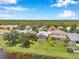 Aerial view of homes with manicured lawns bordering a lake, surrounded by lush green trees and blue skies at 899 Addison Ne Dr, St Petersburg, FL 33716