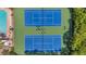 Overhead shot of a tennis court showcasing net, court lines, and green and blue court paint with surrounding greenery at 899 Addison Ne Dr, St Petersburg, FL 33716