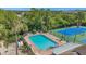 Aerial view of community pool with tennis court and lounge chairs in lush, tropical landscaped community at 899 Addison Ne Dr, St Petersburg, FL 33716