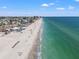 Aerial shot showcases white sand beach, waterfront condos, and turquoise ocean waters on a sunny day at 9755 Harrell Ave # 101, Treasure Island, FL 33706