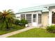 Cozy home exterior with a charming enclosed porch and lush, tropical landscaping at 101 Cambridge Trl # 194, Sun City Center, FL 33573