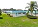Well-maintained exterior showcasing lush green lawn, palm trees, and light blue roof and door at 101 Cambridge Trl # 194, Sun City Center, FL 33573
