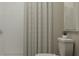 Bright bathroom featuring tiled shower with modern shower curtain, and toilet at 10198 Trumpet Honeysuckle Way, San Antonio, FL 33576