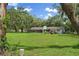 Rear exterior view of a single-story home with a covered porch, framed by trees and grass at 11029 Clay Pit Rd, Tampa, FL 33610