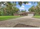 Paver driveway leads to a traditional-style brick home, enhanced by mature trees and lush landscaping at 11029 Clay Pit Rd, Tampa, FL 33610