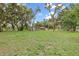 Long view of home across large front yard with mature shade trees at 11029 Clay Pit Rd, Tampa, FL 33610