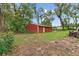 A red outbuilding with a white door on a grassy lot with scattered trees at 11029 Clay Pit Rd, Tampa, FL 33610