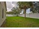 A green backyard features lush grass, mature trees, and a white fence for privacy and security at 11415 Bright Star Ln, Riverview, FL 33569