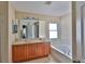 Bathroom featuring a double sink vanity, large mirror, and a soaking tub with tile surround at 11415 Bright Star Ln, Riverview, FL 33569