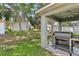 Backyard featuring a covered patio with a grill, lush green lawn, and mature trees at 11708 Crest Creek Dr, Riverview, FL 33569
