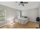 Well-lit bedroom with wood floors, a ceiling fan, and large window overlooking a lush, tropical landscape at 11708 Crest Creek Dr, Riverview, FL 33569