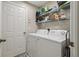 Functional laundry room with washer, dryer, and wire shelving for storage at 11708 Crest Creek Dr, Riverview, FL 33569
