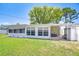 Green backyard with grass and the back of the house with a covered porch and utilities at 12033 82Nd Ave, Seminole, FL 33772