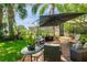 Seating arrangement under umbrella on brick paver patio with view of the house at 12134 Tournament View Ave, New Port Richey, FL 34654