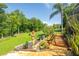 Scenic backyard featuring a beautifully landscaped walkway, lush greenery, and manicured lawn for outdoor enjoyment at 12134 Tournament View Ave, New Port Richey, FL 34654