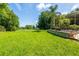 Lush backyard overlooking the golf course, mature trees, and the charming screened-in lanai with outdoor seating at 12134 Tournament View Ave, New Port Richey, FL 34654