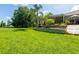 Expansive backyard featuring lush green lawn, mature trees, and a charming screened-in lanai with outdoor seating at 12134 Tournament View Ave, New Port Richey, FL 34654