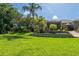 Expansive backyard featuring lush green lawn, mature trees, and a charming screened-in lanai with outdoor seating at 12134 Tournament View Ave, New Port Richey, FL 34654