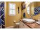 Well-lit bathroom featuring a vessel sink on a granite counter, complemented by a framed mirror and a window with plantation shutters at 12134 Tournament View Ave, New Port Richey, FL 34654