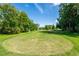 Picturesque golf course view with lush green grass, mature trees, and a clear blue sky on a sunny day at 12134 Tournament View Ave, New Port Richey, FL 34654