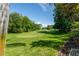 Picturesque golf course view with lush green grass, mature trees, and a clear blue sky on a sunny day at 12134 Tournament View Ave, New Port Richey, FL 34654