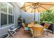 Outdoor patio area with a wooden dining set under a large umbrella, surrounded by lush greenery and plants at 12134 Tournament View Ave, New Port Richey, FL 34654