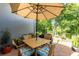 Charming outdoor dining area with a wooden table and chairs under a large umbrella, set against a backdrop of lush greenery at 12134 Tournament View Ave, New Port Richey, FL 34654