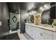 Bathroom featuring dual sinks, decorative mirrors, and glass shower doors; dark walls offer a modern style at 12937 Ogden Glade Rd, Dade City, FL 33525