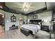 A modern main bedroom with tray ceilings, dark trim, wood-look flooring, and an adjoining bathroom at 12937 Ogden Glade Rd, Dade City, FL 33525