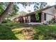 Lush backyard with patio, grill, tropical plants, and partially screened-in back porch at 1380 Azalea Dr # 1701, Dunedin, FL 34698