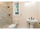 Bathroom showcasing a tiled shower, pedestal sink, and toilet near a window at 1413 Bayshore Blvd # 11, Dunedin, FL 34698
